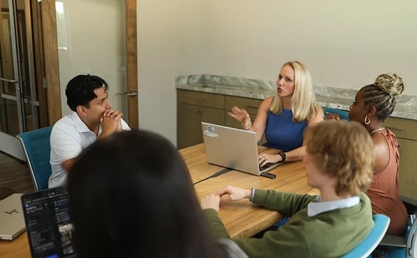Team meeting around a table with laptops